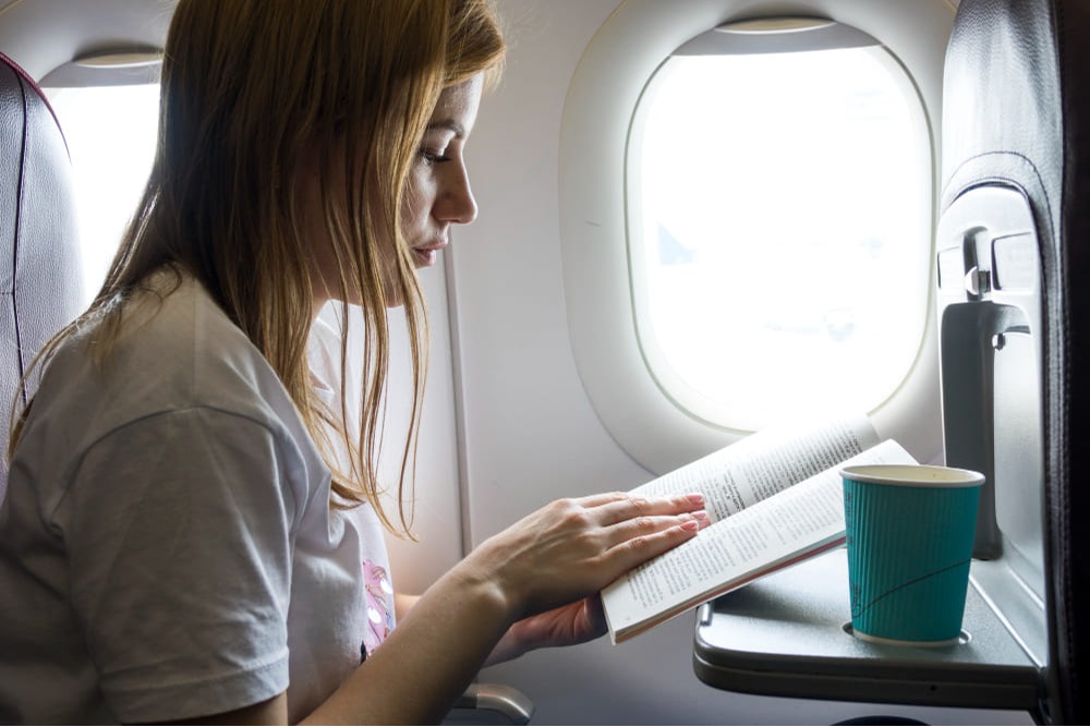 Mulher lendo livro dentro de avião